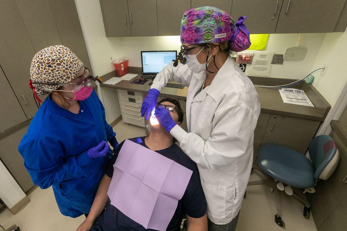 两名火博体育的牙科学生正在治疗一名病人